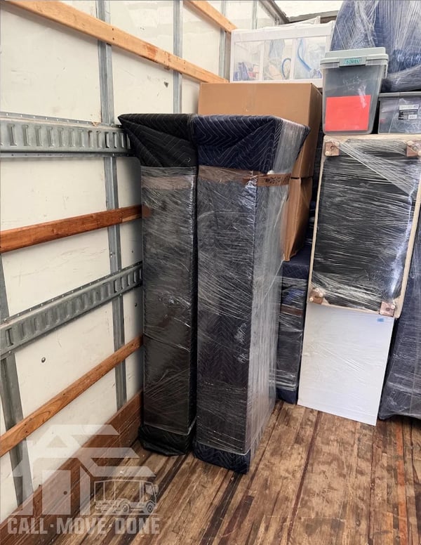 Quilted moving blankets and shrink wrap protecting furniture inside the truck