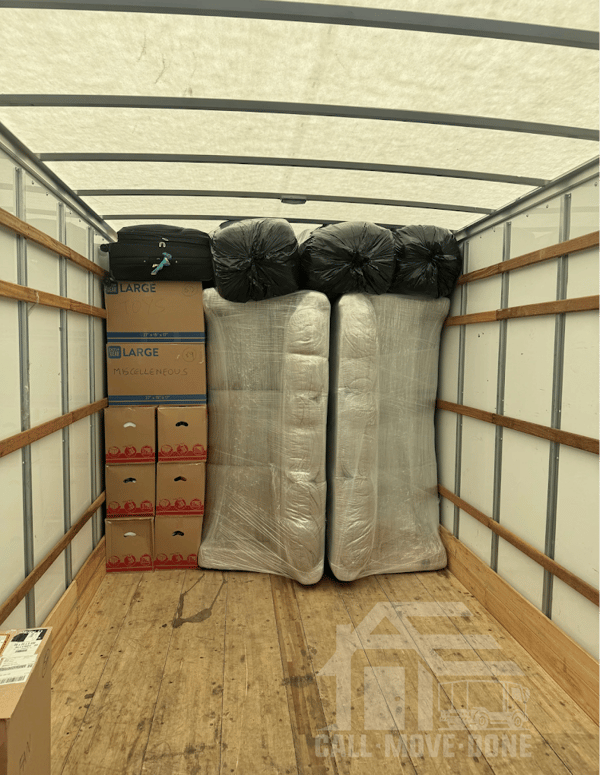 Truck interior loaded with wrapped mattresses and labeled boxes