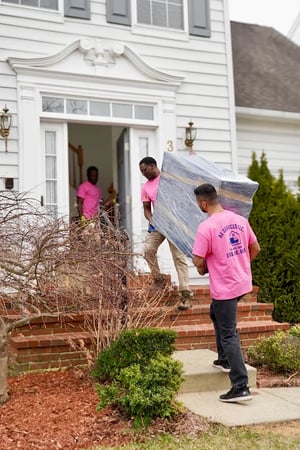 Movers carrying a wrapped piece out the front door