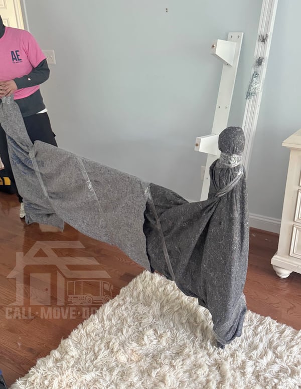 Movers covering a table in quilted moving blankets