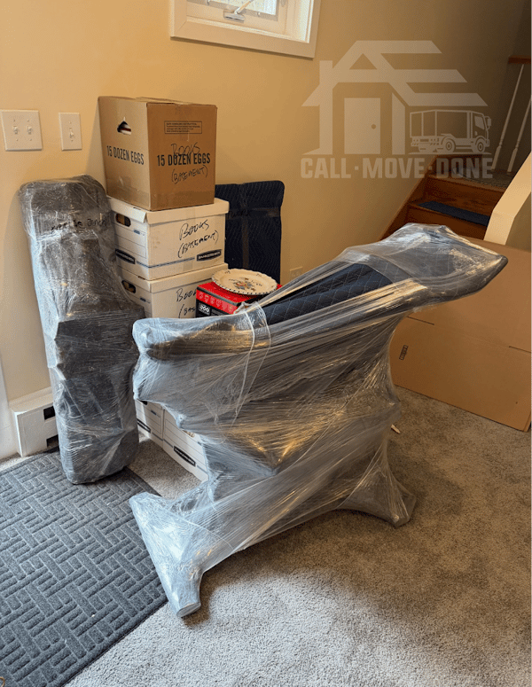 Antique desk fully shrink-wrapped next to labeled boxes