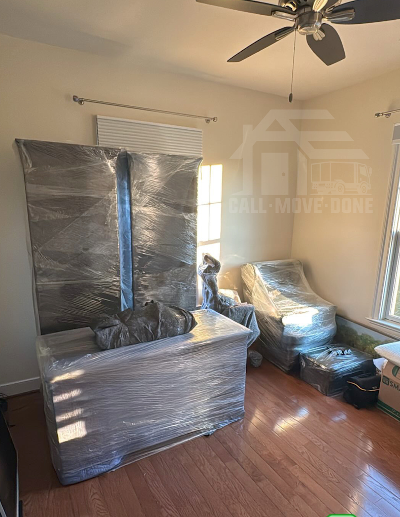 Living room furniture wrapped in blankets and shrink wrap before a move